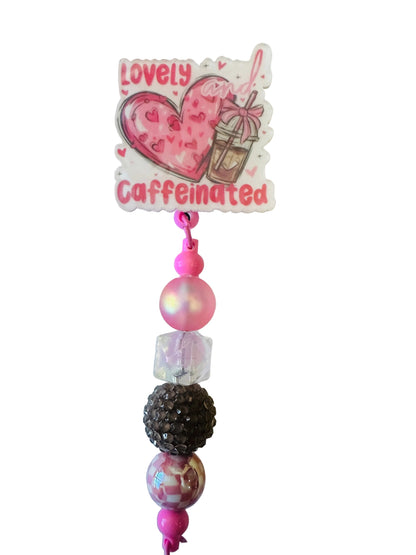 Pink beaded charm with a heart design and 'Caffeinated & Lovely' text on a light background